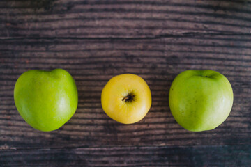plant-based food, group of  green apples lined up with a unique yellow one in the centre