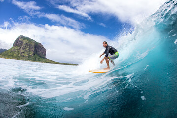 Surfing on big waves against the backdrop of picturesque mountains and beautiful clouds