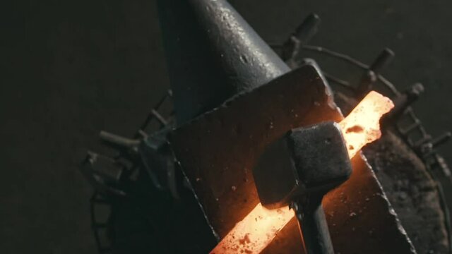 Forge workshop. Smithy manual production. Hands of smith with hammer hit on glowing hot metal, on the anvil, the forging process. Blacksmith makes iron products for manufacture of fireplace, stove.