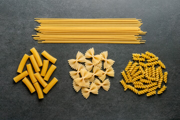 Different types of macaroni on a matt granite table.
