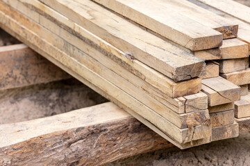 piled stack of natural brown rough wooden boards at construction site. stacked wood planks.
