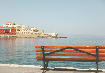 Fototapeta na wymiar Old greek town with bright houses on a background of the sea. In the foreground a panoramic bench 
