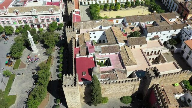 Aerial forward shot of tourists at Plaza del Triunfo amidst buildings, drone flying over people in city - Seville, Spain