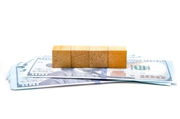 Wooden cubes and dollar bills. A pile of dollars lie on the table and on them lies four identical cubes. First-person view from below, in macro