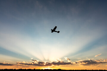 Light Aircraft flying just before sunset with rays of sunlight peaking through the clouds on the horizon.  © Ryan