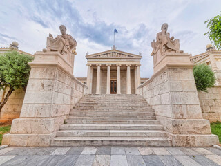 Obraz premium impressive sky over Plato and Socrates the ancient Greek philosophers statues in front of the national academy of Athens, Greece