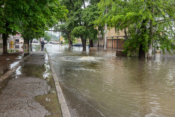 Fototapeta na wymiar Odessa, Ukraine - May 28, 2020: driving car on flooded road during flood caused by torrential rains. Cars float on water, flooding streets. Splash on car. Flooded city road with large puddle