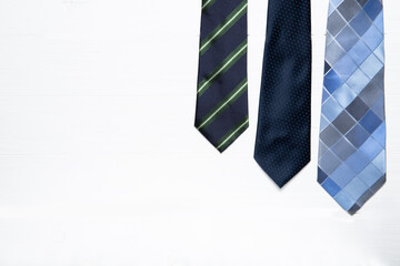 Men's ties on a white wooden background. Place for text