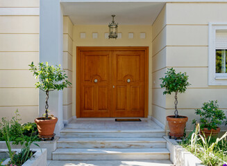 elegant house entrance portico with natural wooden doors and potted plants