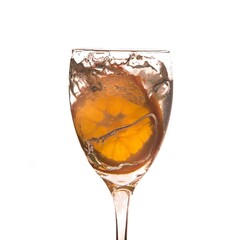 Lemon/lime splashing in water in a wine glass behind a white background; Vegetables splashing in water