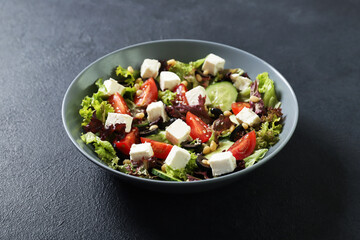 Fototapeta na wymiar Plate with fresh vegetables salad on a black background. Vegetarian food