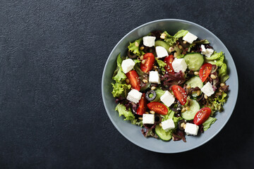 Plate with fresh vegetables salad on a black background. Place for text