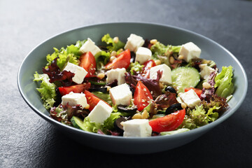 Plate with fresh vegetables salad on a black background. Vegetarian food
