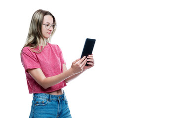 Fototapeta premium A young girl in jeans with a tablet in her hands. Isolated on a white background. Space for text.