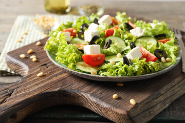 Plate with tasty greek salad of fresh vegetables on wooden background