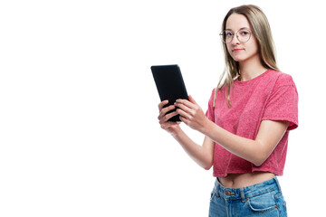Fototapeta premium A young girl in jeans with a tablet in her hands. Isolated on a white background. Space for text.