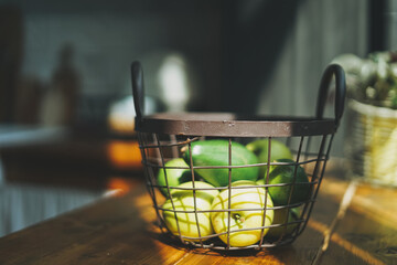 Fototapeta na wymiar Ripe raw fresh green avocado and apples in metal basket in kitchen hard sun light