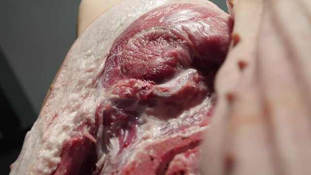 Hanging pork carcass turning towards the camera. Close up