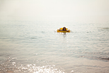 The child floating on water in a large inflatable circle. Young girl prefer swimming relaxation