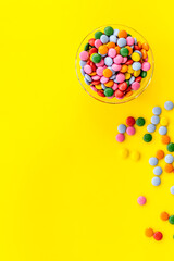 Colorful sweets on yellow desk from above space for text