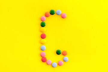 Letter G - alphabet made with sweets on yellow from above