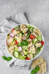 Vegetarian fattoush salad. Traditional Middle Eastern salad with toasted pita bread and vegetables. Lebanese cuisine. Light grey stone background. Top view.