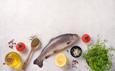 fresh river trout  fish with lemon, tomatoes and spices on a white table