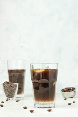 Espresso tonic, refreshment summer drink with tonic water, coffee and ice cubes, light grey concrete background. Trendy coffee drink.