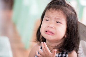 An Asian little child girl is crying, sad tears from being scolded by an adult. Baby kid 3 years old. In the summer temple area. The concept of sadness for young children.