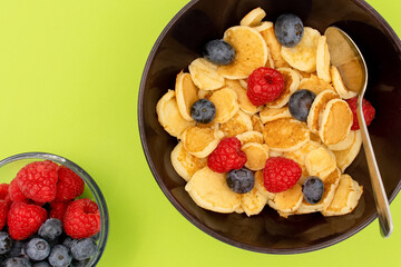 A bowl with mini pancake cereal. Trendy food. Tiny cereal pancakes with blueberries and raspberries