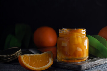 orange jam on a dark background .glass jar of orange jam with fresh fruit