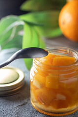 orange jam on a dark background .glass jar of orange jam with fresh fruit