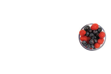 Blueberries amd raspberries in a transparent bowl on a white background. Healthy lifestyle concept