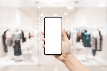 Mockup white blank screen mobile phone. Hand holding smartphone with blurred women clothing store...
