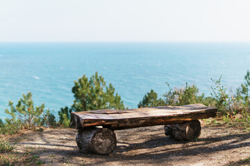 A single bench made of natural wood in the forest with a view of the sea.