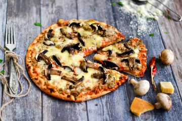   Home made Tuna italian style  ketogenic pizza  served uncut on a wooden board with fresh  cherry tomatoes, basil and mushroomns in a rustic kitchen on an old wooden table