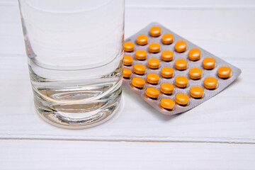 A package of orange tablets is placed on a white background
