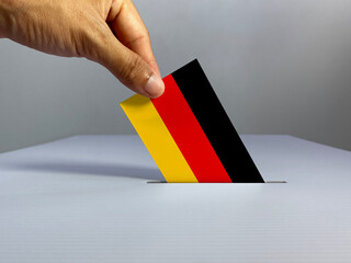Voting / election concept: hand holding voting card with country national flag, inserting it into...