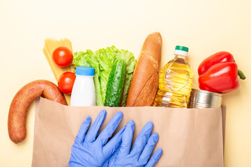 Grocery set in paper bag and hands in and medical gloves. Delivery service during quarantine, coronavirus covid-19. Top view
