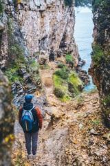 man with backpack at footpath canyon leading to sea beach