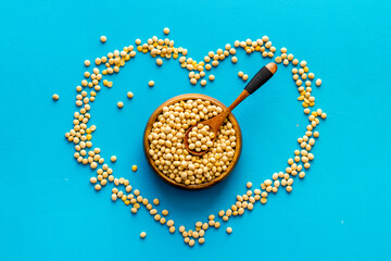 soybeans in bowl and heart sign on blue background from above