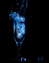 Splashes and drops of water in a glass are isolated on a black background.