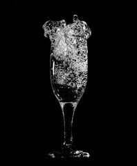 Splashes and drops of water in a glass are isolated on a black .