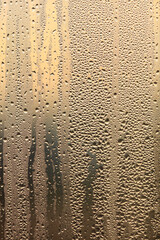 Drops of water on a glass window at dawn as an abstract background.