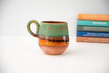 colorful handmade ceramic coffee cup with books on the table