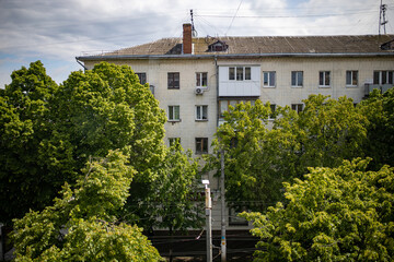 Old five-storey house against trees and sky