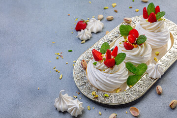 Traditional meringue dessert Pavlova with strawberries and pistachios.