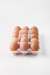 food photography of clean plastic pack of brown farm chicken eggs close-up on a light gray background isolated