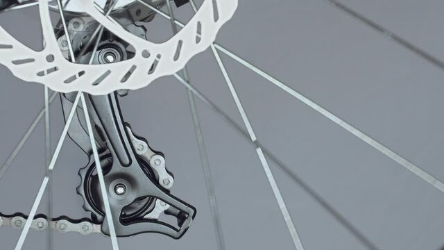 Rear derailleur with jockey wheels, idler lower and upper pulley. Gearshift on mountain bike MTB. Work of chain drive. Shift gears. Changes speeds. Closeup shot. Disc brake with spokes on foreground