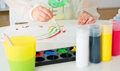 Boy painting with a brush and vegetable colors and with a child's drawing